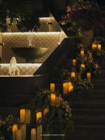 A staircase is transformed into a romantic pathway with dozens of candles in glass hurricanes and scattered greenery.