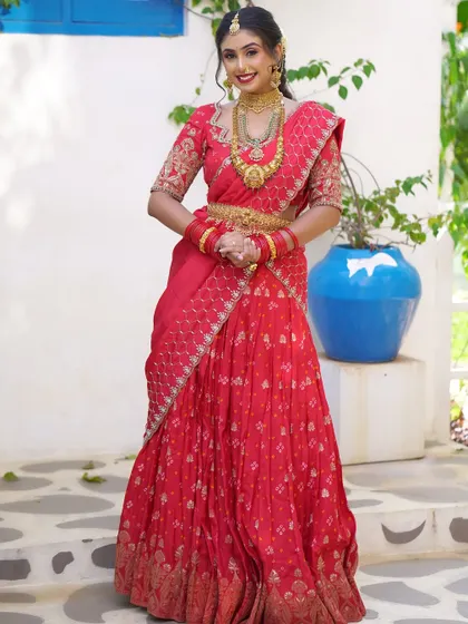A full view of a bride in a beautifully draped red lehenga-saree. My service includes expert saree draping to ensure the entire silhouette is perfect from head to toe.