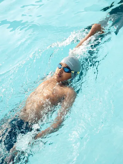 Every stroke is a step closer to greatness. An advanced swimmer practices their backstroke, focusing on reach and rotation.