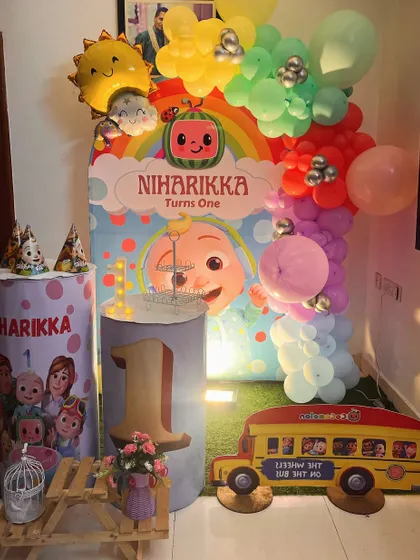 A vibrant Cocomelon theme for a first birthday, featuring a colorful backdrop, character props, and a custom-printed pedestal with the number '1'.