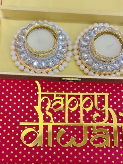 A detailed look at a 'Happy Diwali' box containing two exquisite pearl and crystal diya holders.