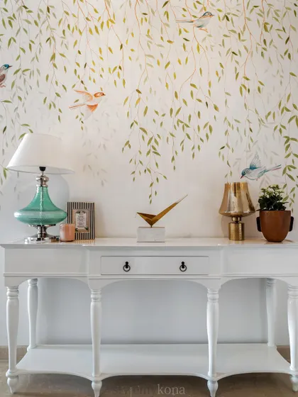 The hand-painted mural of birds and weeping willows adds a soft, artistic touch to the foyer wall.