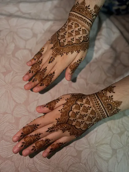 A lighter take on the traditional back-hand design, with a central geometric pattern and delicate floral vines on the fingers.