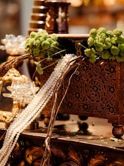 A close-up of a carved wooden box overflowing with pearls, set next to a classic candelabra. These details evoke a sense of discovered treasure within the 'Lost City'.