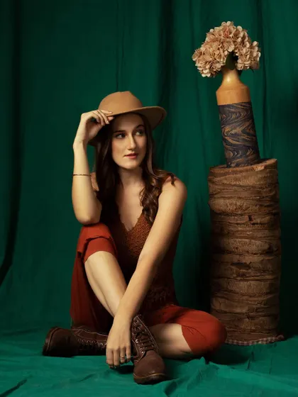 A full-length seated pose. This is a great way to showcase the entire outfit, including the boots, in a natural way.