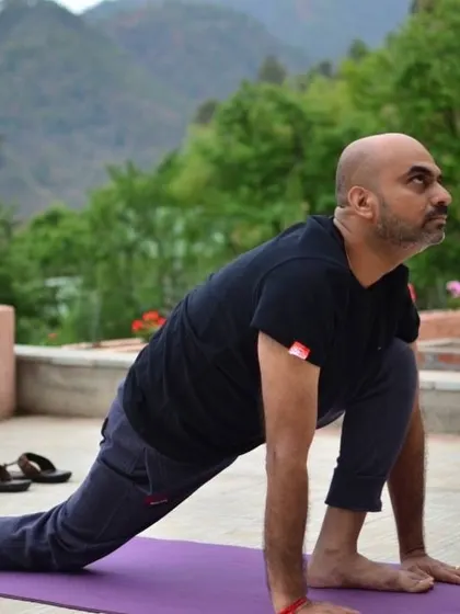 A student practices Ashwa Sanchalanasana, the equestrian pose, against a mountain backdrop during a retreat based TTC. The environment enhances the yogic experience.