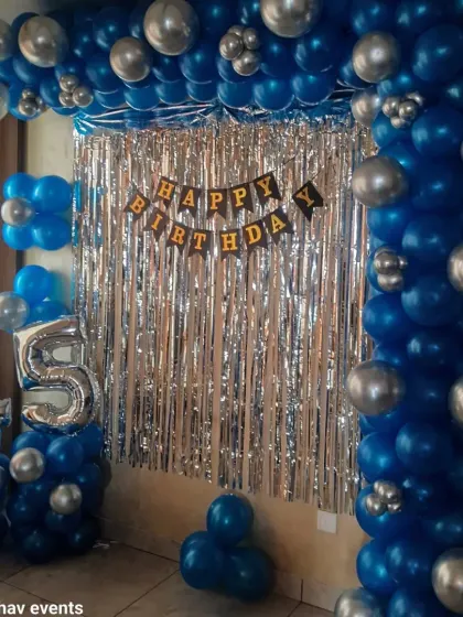 A stylish wall decoration for a 25th birthday. This setup features a blue and silver balloon frame around a silver shimmer curtain, with 'Happy Birthday' and number '25' foil balloons.