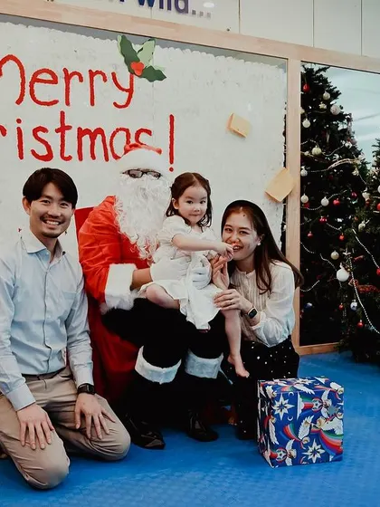A family poses for a photo with Santa Claus next to the Christmas tree.