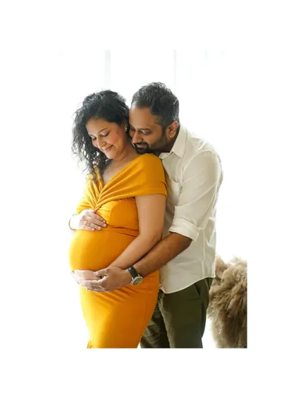A bright, high-key portrait of a couple sharing a loving embrace, showcasing their joy and anticipation.