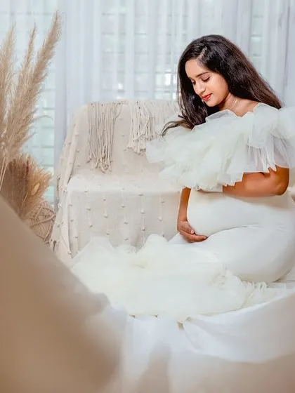 A beautifully framed shot of the mother-to-be, seen through a soft foreground. This artistic composition draws all the attention to her serene expression.