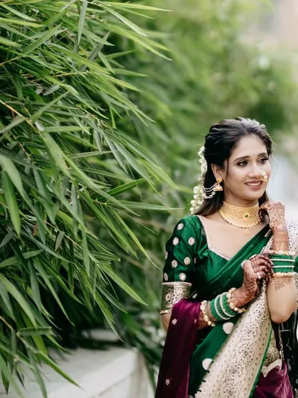 The bride, adorned in her traditional green saree and gold jewelry, adjusts her bangles. This candid shot captures a moment of quiet elegance and highlights the beautiful details of her bridal attire.