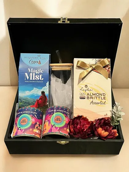 This sophisticated corporate Diwali hamper is packed in a reusable black trunk box. It contains a selection of gourmet Indian snacks, assorted brittles, fragrant tea, and a stylish glass tumbler with a bamboo lid.