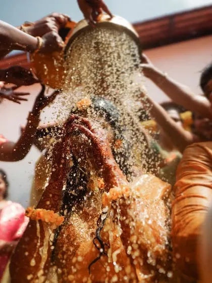 A bride getting drenched during her Haldi bash. We are not afraid to get in the middle of the action to capture these unforgettable, high-energy moments.