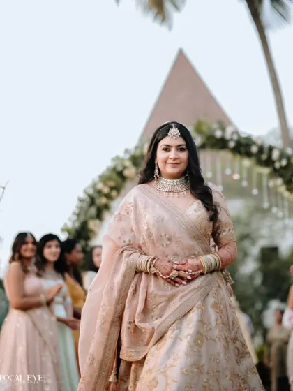 A close-up portrait of the bride, highlighting her intricate jewelry and the happy anticipation on her face as she walks down the aisle.