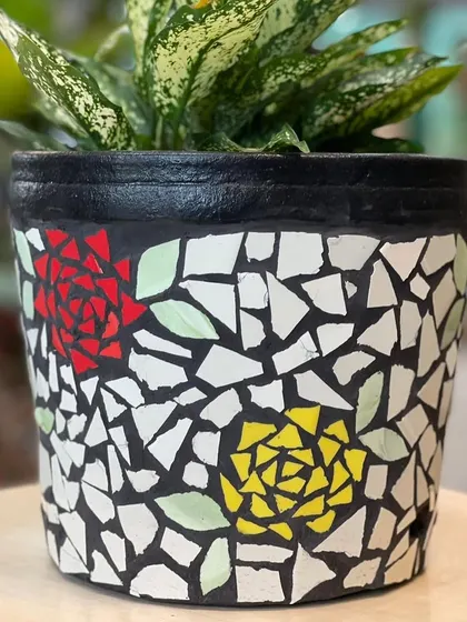 A close-up of a mosaic planter with a rose design. Each pattern is created by hand with cut ceramic tiles over a terracotta pot, ensuring that every planter is a unique piece of art.