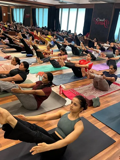 Students building core strength together in Navasana (Boat Pose) during a community class.