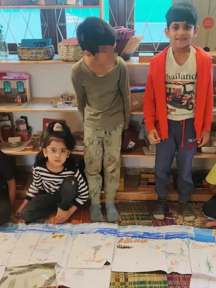 A group of children proudly display their massive, hand-drawn timeline charting the evolution of life on Earth. This month-long collaborative project involved research, drawing, painting, and immense perseverance.