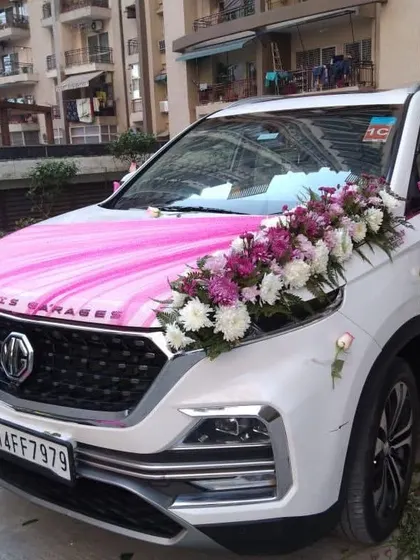 This MG Hector features a stylish arrangement of white and purple flowers on the bonnet, paired with a bright pink fabric drape. I can match the decoration to any theme or colour preference.