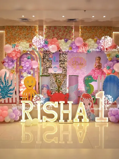 Dive into an underwater adventure with a detailed Mermaid theme. This stage combines shimmering backdrops, character cutouts of sea creatures and mermaids, and custom light-up letters to create a magical ocean kingdom for a first birthday.