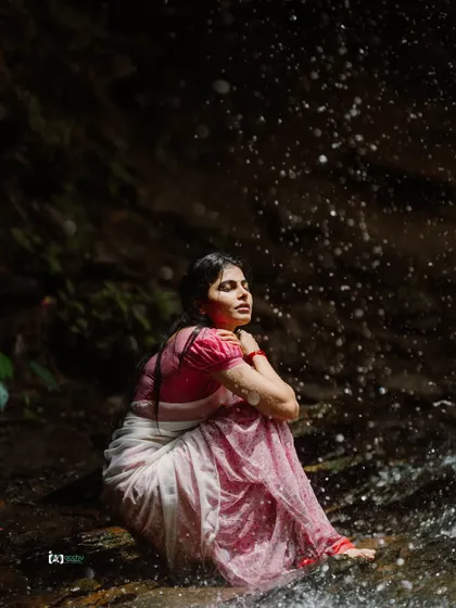 A truly artistic and conceptual shoot. The subject is partially submerged in water near a waterfall, creating a serene and almost surreal image that connects fashion with the elements.