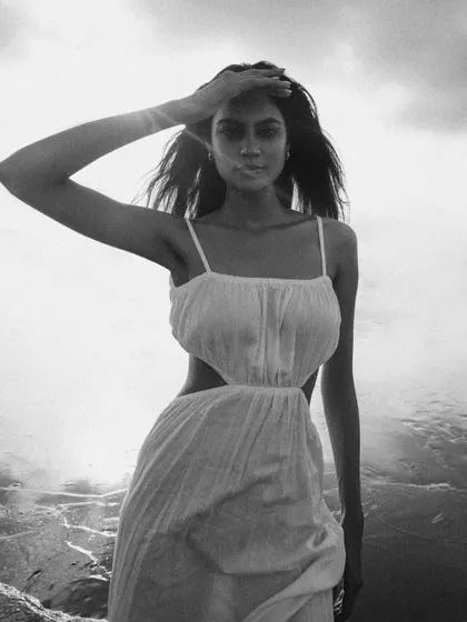 A beautiful black and white beach portrait. The backlighting from the sun creates a dreamy, ethereal glow, capturing a moment of natural elegance.