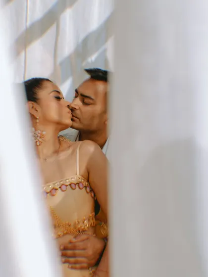 A passionate and romantic moment between the couple, captured artistically through a sheer curtain.