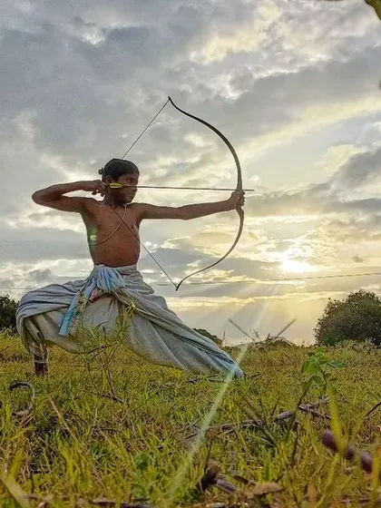 A young archer practices his form against the setting sun. The true aim is not just the target, but the perfection of one's own form, focus, and spirit.