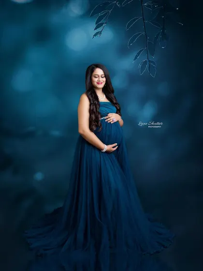 A serene portrait in a flowing teal gown. The moody, artistic background with soft bokeh gives the image a dreamy, underwater feel.