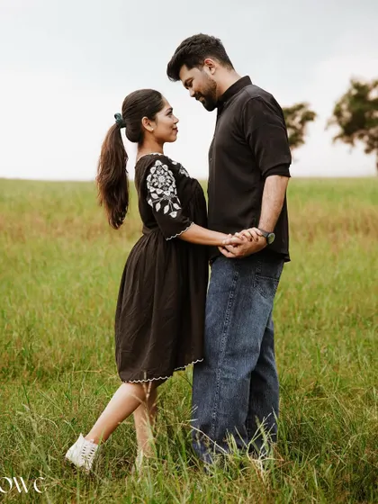 A sweet and romantic pose in a field, with the couple looking into each other's eyes.