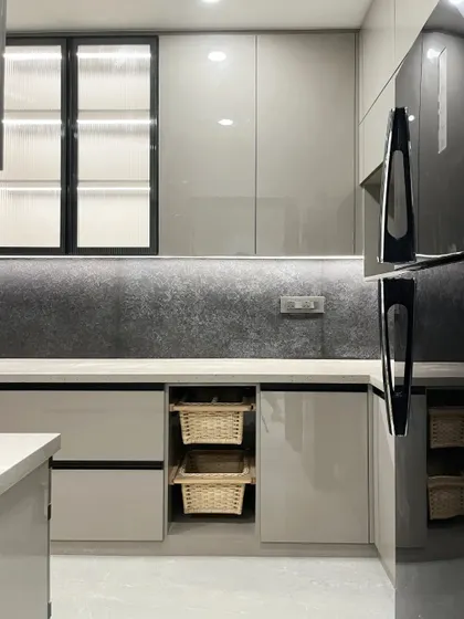 Another angle of the grey kitchen, showing the glossy finish of the cabinets and the reflection of light, which helps to make the space feel larger.