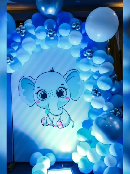 A cute baby elephant graphic on a backlit panel, surrounded by a blue balloon arch. The lighting makes the character pop.