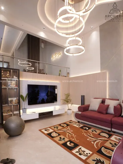 A grand, double-height living room with a statement ring chandelier, a sleek white TV unit, and a mezzanine overlook, creating a sense of scale and luxury.