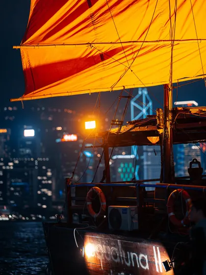 A close-up of the vibrant red sail of a junk boat against the glittering city lights. I focused on the details and textures to capture the feeling of being on the water at night.