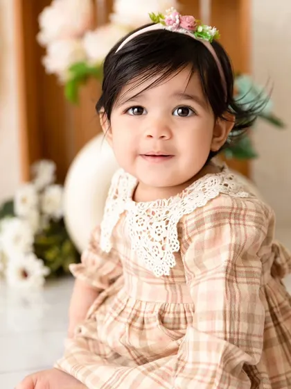 A sweet, smiling portrait from the same session, showcasing the soft lighting and floral details of the setup.