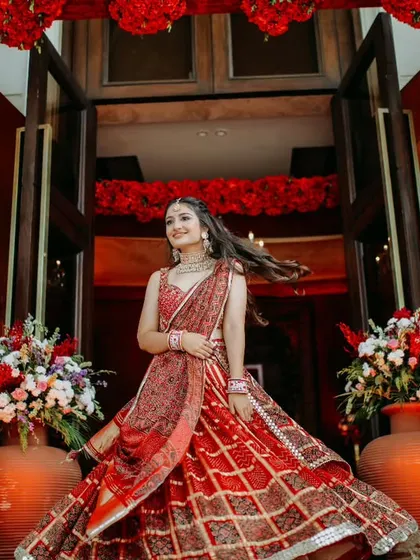 A joyful, twirling shot of a bride at her Mehendi or Sangeet. The vibrant red decor and her flowing lehenga create a picture of pure celebration.