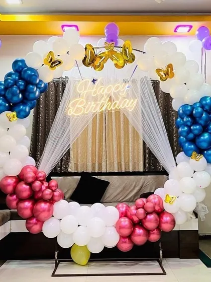 A unique birthday balloon ring in white, pink, and blue, with a sheer curtain draped in the center.