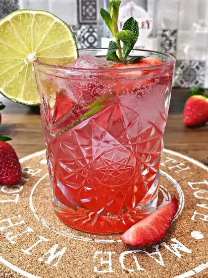 A classic Strawberry Mojito. This refreshing drink is made with fresh strawberries, mint, and lime, served in a beautiful crystal-cut glass.