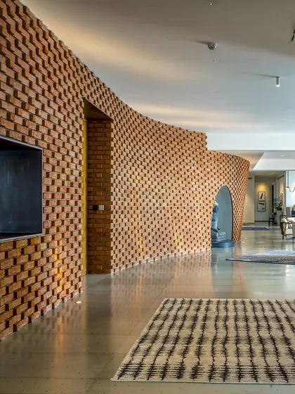 In the Sampurna Residence, we used a curving brick wall to create an 'animated streetscape' within the home. This element guides movement and defines space, transforming a simple corridor into an artistic and experiential journey.