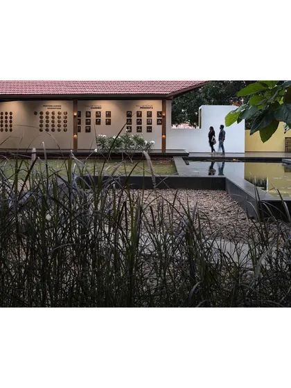 The landscape design for the museum guides visitors through a series of spaces. Here, a walkway passes between a lotus pond and a pavilion wall displaying historical photographs.