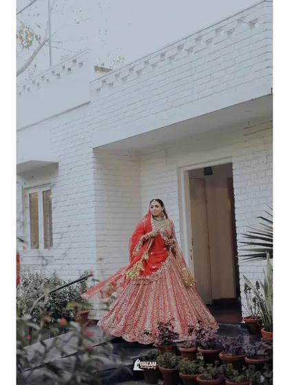 A full-length shot of bride Hashmeeta in her stunning red lehenga, posing at the entrance of her wedding venue.