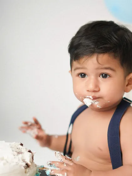 A close-up of the birthday boy with frosting on his face. This is the signature shot of any successful cake smash session.
