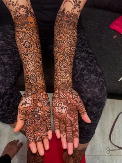 The complete bridal henna for a client, featuring personalized initials. The design covers the hands and arms in a dense, intricate pattern that is truly breathtaking.