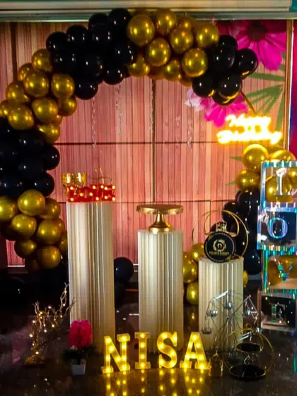 For a bold and dramatic look, we designed this black and gold metallic balloon arch. The setup is completed with matching pedestals, marquee letters for the name, and other decorative props to create a cohesive, high-impact party theme.