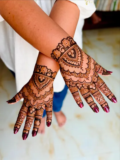 Wrist-length Indian mehendi for a client attending her cousin's engagement, featuring a central heart motif and dense traditional patterns.
