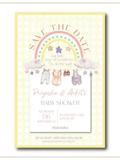 A sweet and simple 'Save the Date' for a baby shower. The design features a watercolor rainbow and tiny baby clothes hanging on a line, with the phrase "our little ray of sunshine is on the way."