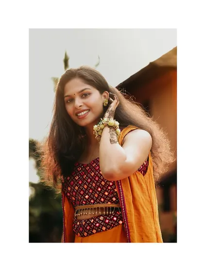 A happy and bright portrait of a bride at her Haldi ceremony, adorned with floral jewellery.