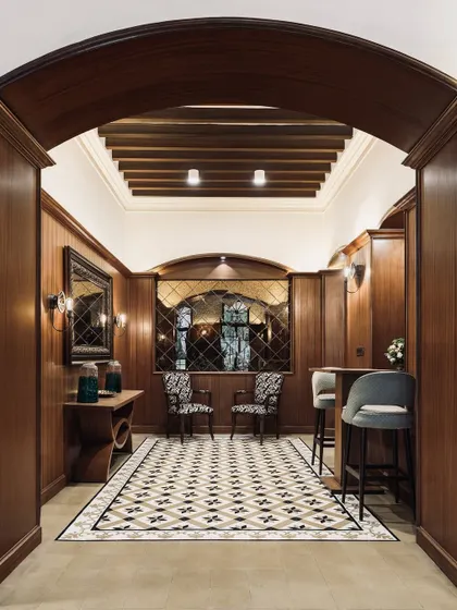 This entryway at The Bangalore Club showcases our approach to heritage interiors. We used dark wood paneling, an arched doorway, and geometric floor tiles to create a space that feels both grand and intimate, honoring the club's historic character.