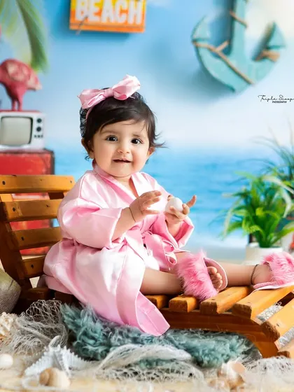 A happy smile from a little one enjoying her beach day. The miniature lounge chair and pink robe complete this adorable summer look.