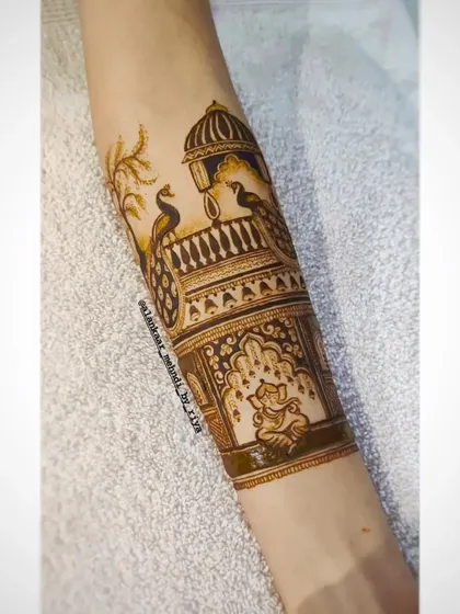 A bridal startup design for the arm, featuring peacocks on a balcony with a Ganesha motif below.
