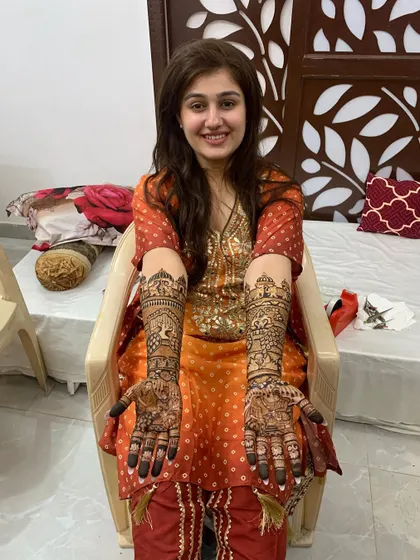 The same happy client posing with her beautiful, full-arm bridal mehndi. The joy on her face is the ultimate reward for my hard work.